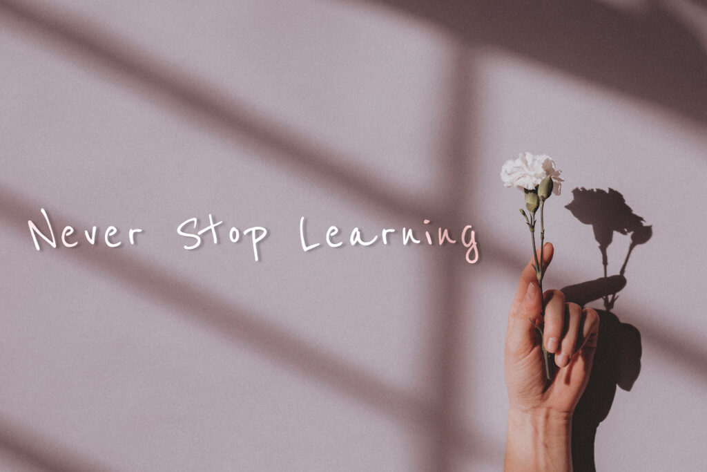 Never stop learning quote on a hand holding flower background